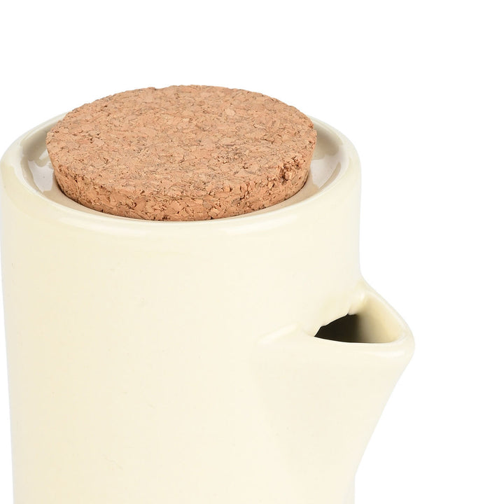 Κοντινή λήψη κεραμικού δοχείου λαδιού σε ιβουάρ χρώμα με φελλό, που αναδεικνύει το στόμιο και τη λεία υφή.