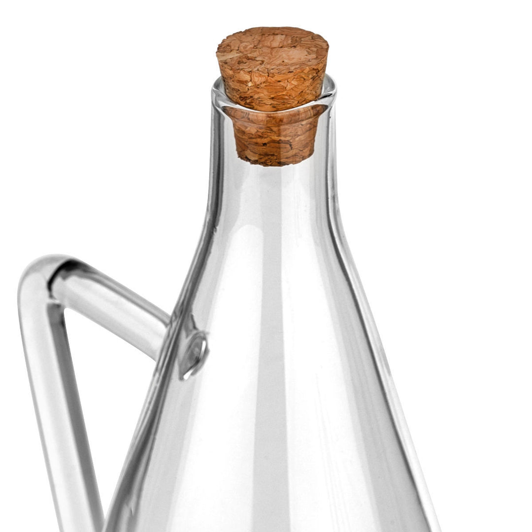 Κοντινή λήψη σε διαφανής γυάλινη κανάτα λαδιού με μακρύ στόμιο και χερούλι, σε λευκό φόντο, με minimal και κομψό σχεδιασμό.