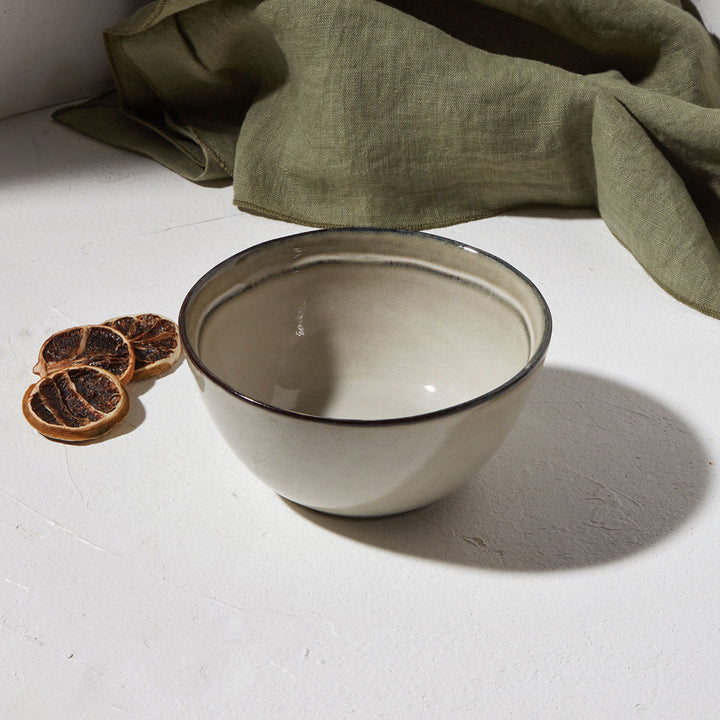 Μπολ για ντιπ Estia από stoneware σε απαλή γκρι απόχρωση, τοποθετημένο σε φωτεινό φόντο με υφασμάτινη λεπτομέρεια και αποξηραμένα εσπεριδοειδή.