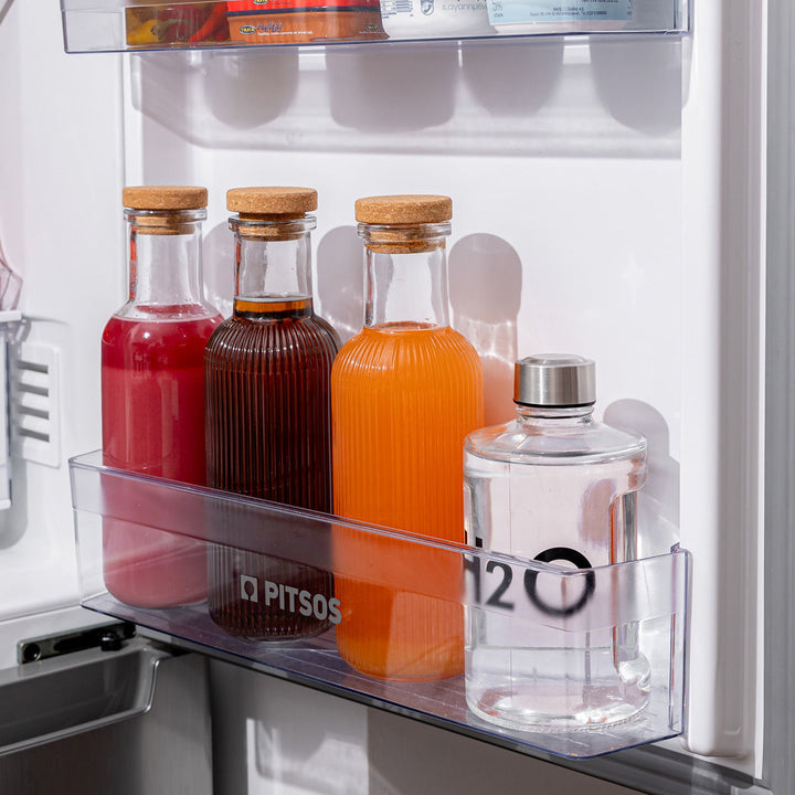 Γυάλινο μπουκάλι με H2O τοποθετημένο στην πόρτα ψυγείου μαζί με άλλα χρωματιστά μπουκάλια.