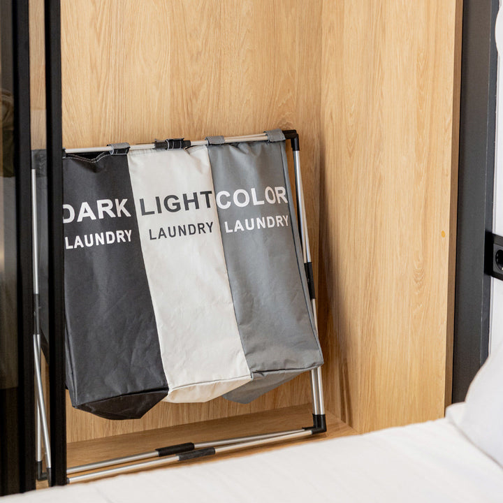 Πτυσσόμενο καλάθι ρούχων Estia σε μαύρο, γκρι και λευκό μέσα σε ντουλάπα υπνοδωματίου.