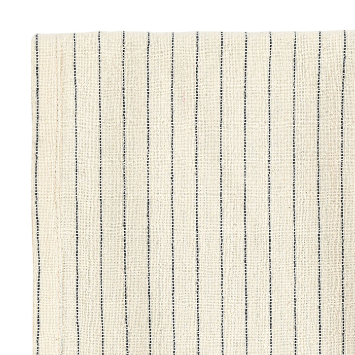 Κοντινή λήψη μπεζ πετσέτας κουζίνας με λεπτές μαύρες ρίγες και φυσική υφή υφάσματος.