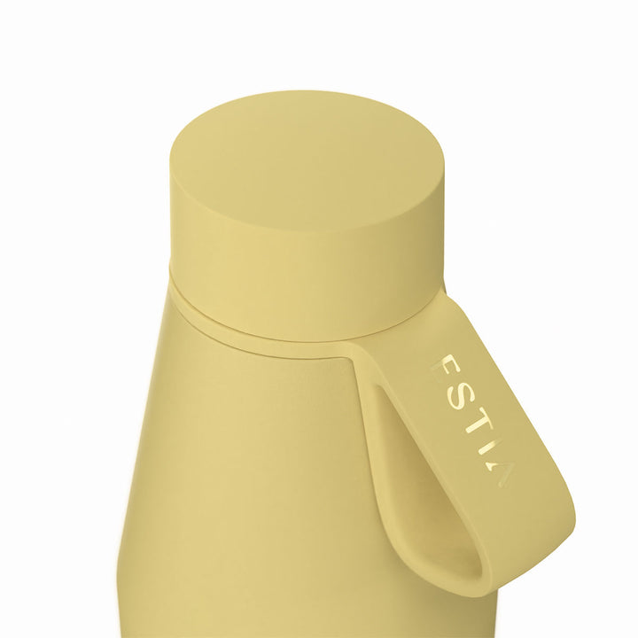 Κοντινή λήψη στο καπάκι και το λουράκι μεταφοράς του θερμός Estia Flow Save the Aegean Sunbeam σε κίτρινη απόχρωση.