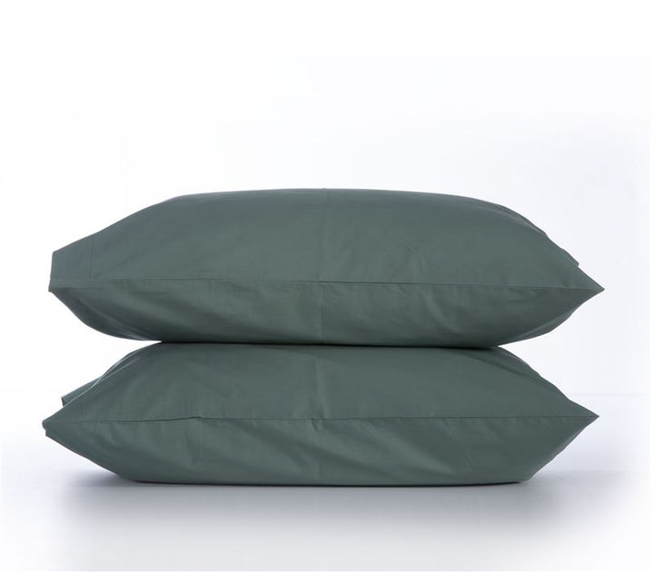 Δύο μαξιλαροθήκες σε σκούρο πράσινο χρώμα, τοποθετημένες η μία πάνω στην άλλη, σε λευκό φόντο που αναδεικνύει την κομψή και φυσική τους απόχρωση, ιδανικές για μοντέρνα ή γήινη διακόσμηση κρεβατοκάμαρας.