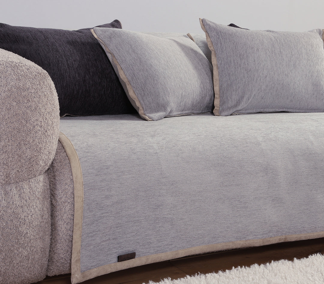 Γκρι ριχτάρι καναπέ με μαξιλάρια σε ανοιχτό και σκούρο γκρι χρώμα, τοποθετημένο σε καναπέ με λευκό χαλί.