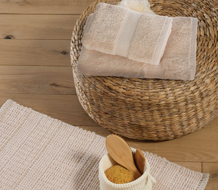 Μπεζ πετσέτες Nef-Nef Homeware τοποθετημένες σε ψάθινο καλάθι μπάνιου με ξύλινα αξεσουάρ και φυσική διακόσμηση.