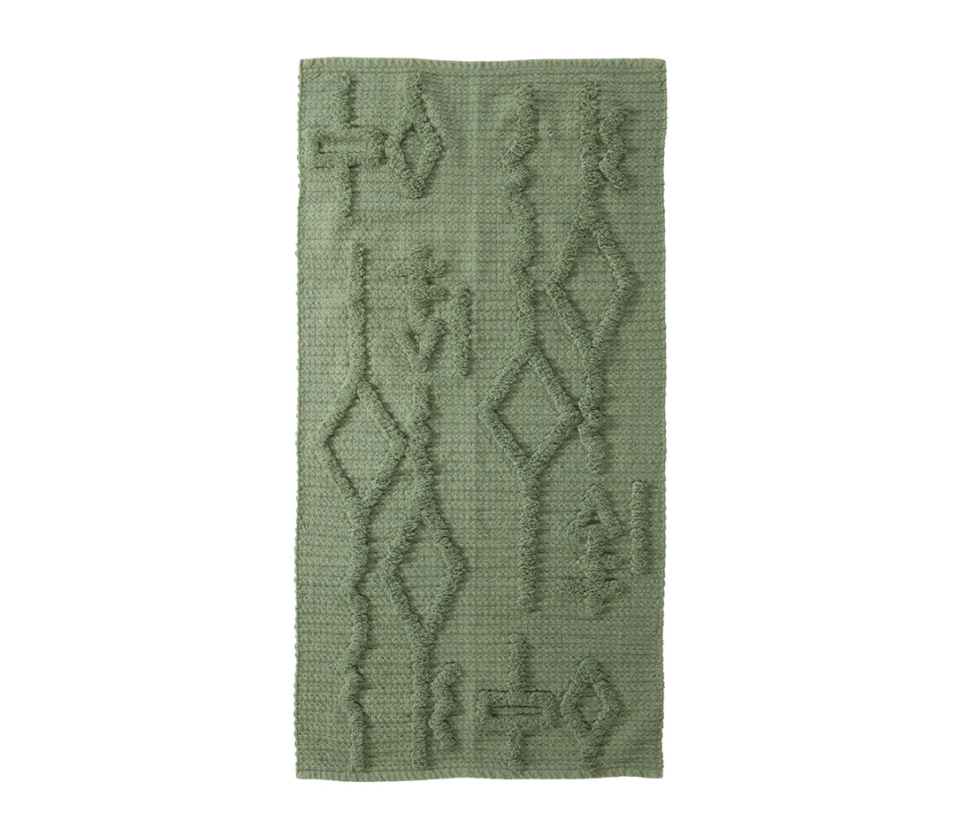 Πράσινο χαλάκι με γεωμετρικά ανάγλυφα σχέδια σε λευκό φόντο.