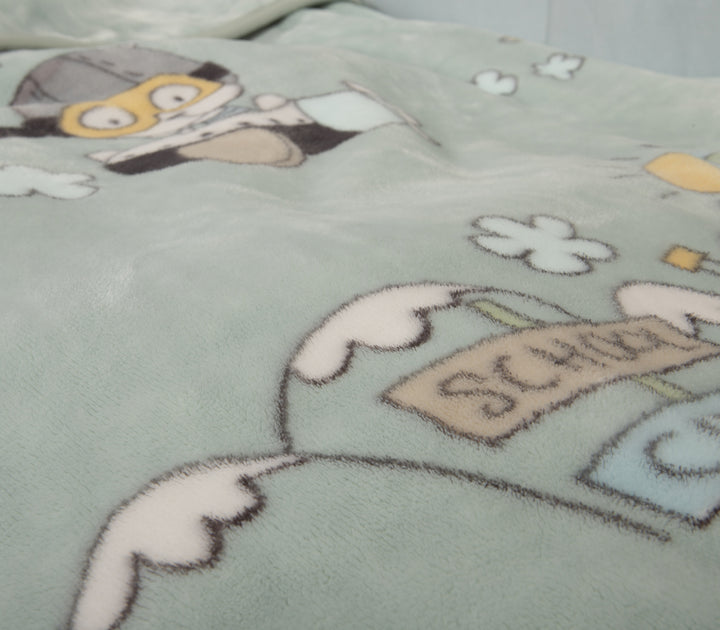 Κοντινή λήψη fleece κουβέρτας σε μέντα χρώμα με παιχνιδιάρικα σχέδια και σκυλάκι ντυμένο πιλότο.