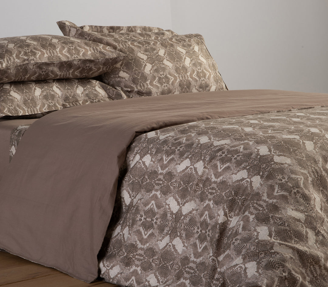 Υπνοδωμάτιο με μπεζ σετ παπλωματοθήκης σε snake print μοτίβο και συνδυασμό μοντέρνων στοιχείων.