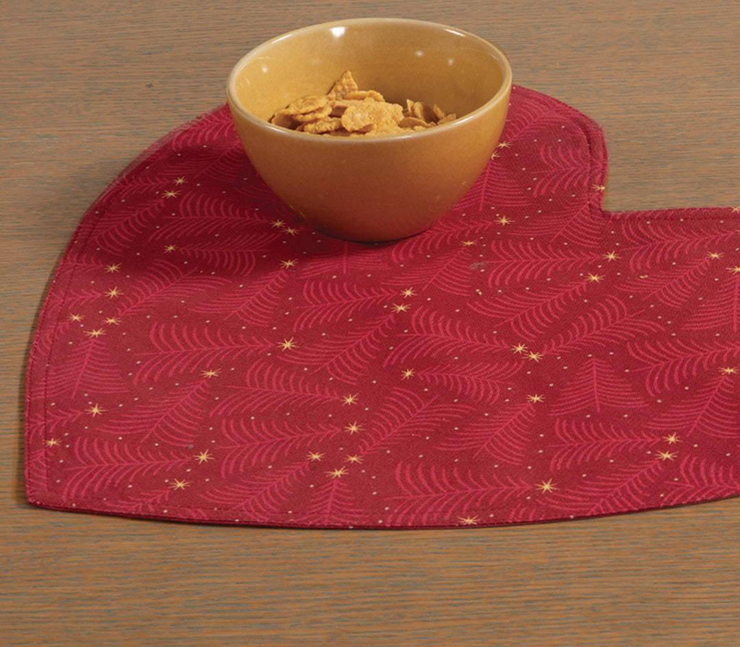 Κόκκινο σουπλά σε σχήμα καρδιάς με χρυσά αστεράκια και σχέδιο κλαδιών, τοποθετημένο σε ξύλινο τραπέζι με μπολ δημητριακών