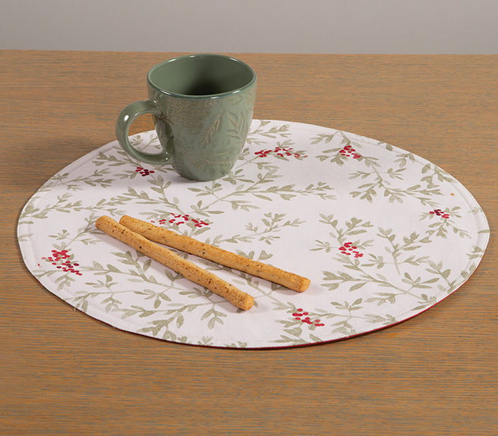 Χριστουγεννιάτικο σουπλά δύο όψεων σε λευκό και κόκκινο φόντο, διακοσμημένο με σχέδια από φύλλα και κόκκινες ραγές, τοποθετημένο σε ξύλινο τραπέζι με πράσινη κούπα και στικς.