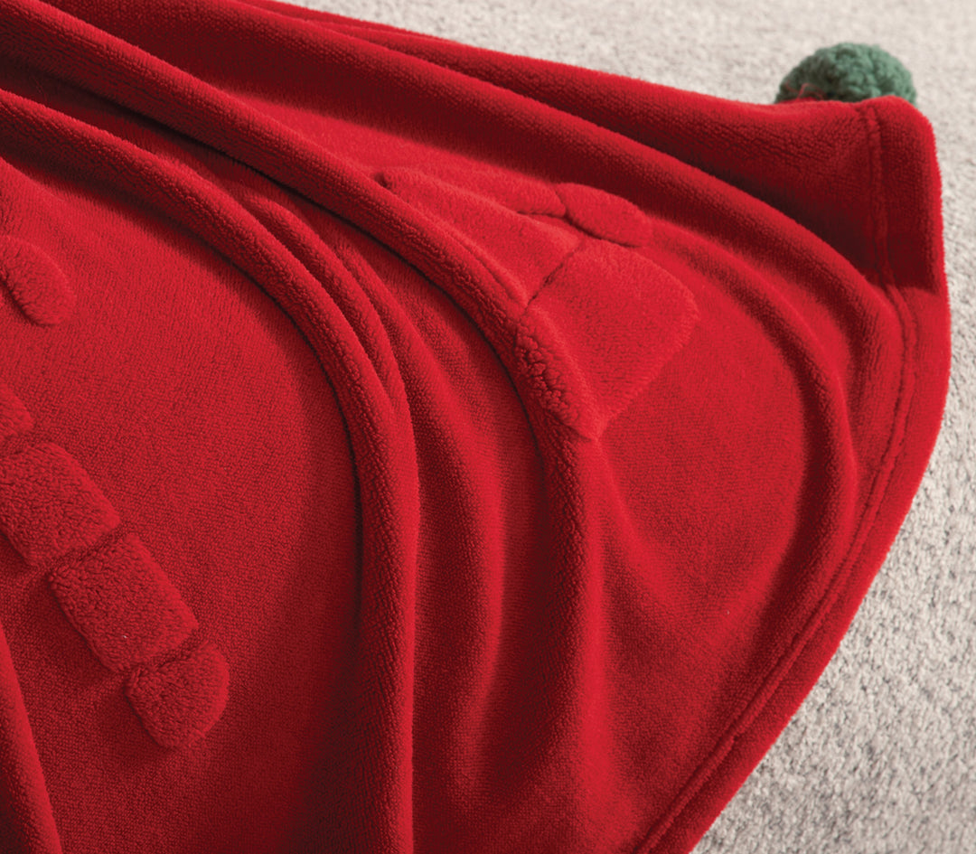 Κοντινό πλάνο κόκκινης fleece κουβέρτας με ανάγλυφα χριστουγεννιάτικα μοτίβα
