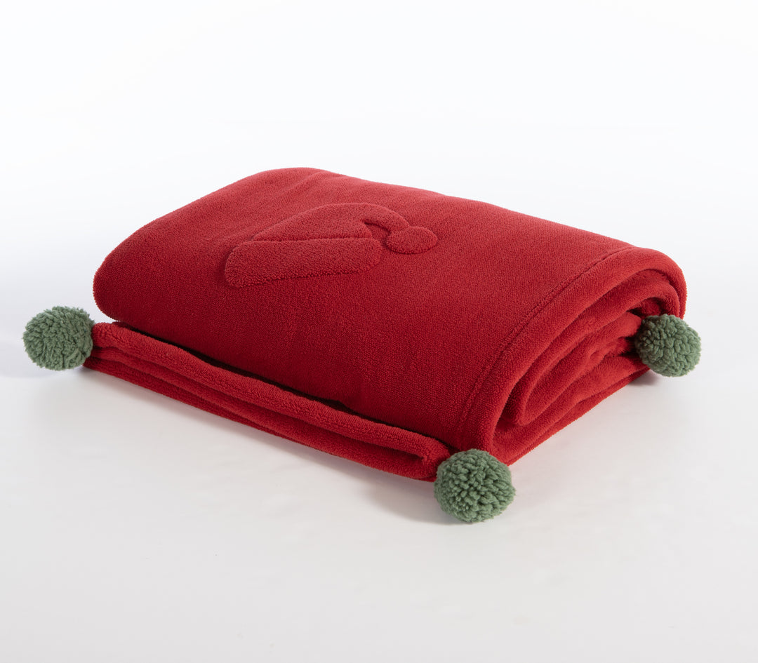 Διπλωμένη κόκκινη fleece κουβέρτα με ανάγλυφο σχέδιο σκούφου Άγιου Βασίλη και φουντίτσες σε πράσινο χρώμα στις άκρες