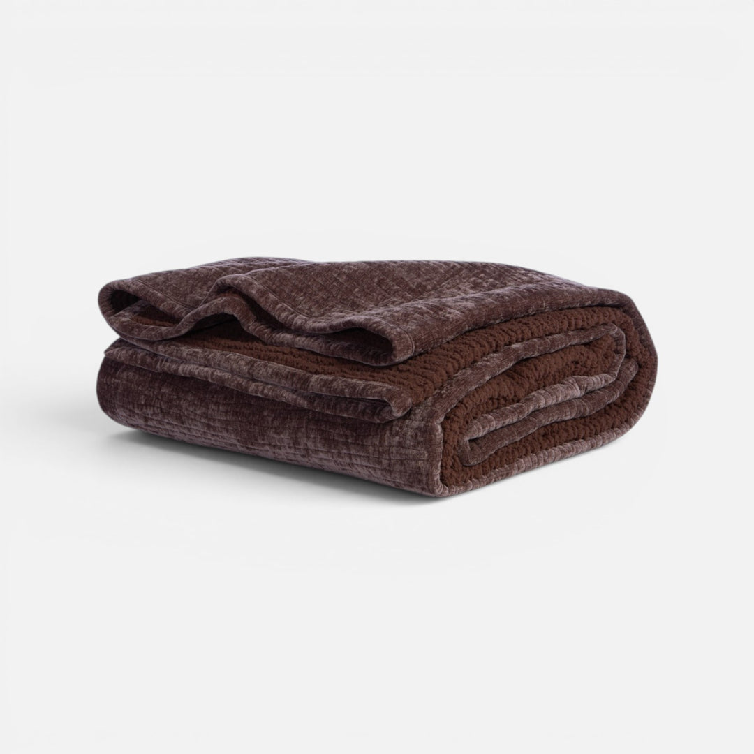 Κουβερλί σε σκούρα καφέ απόχρωση, διπλωμένο ώστε να διακρίνεται η απαλή επένδυση και η βελούδινη όψη του.