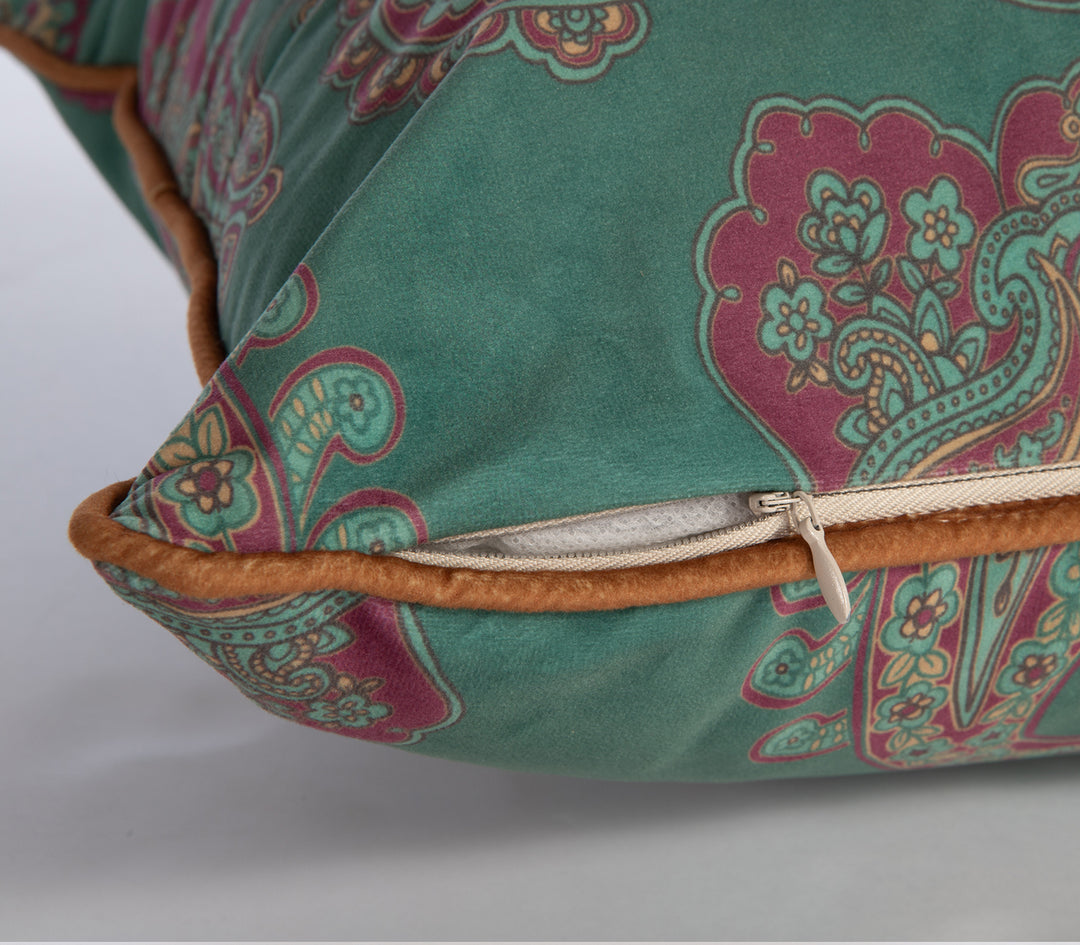 Κοντινό σε πράσινο μαξιλάρι με boho paisley σχέδιο σε κόκκινο και μουσταρδί, με καφέ ρέλι και κρυφό φερμουάρ.