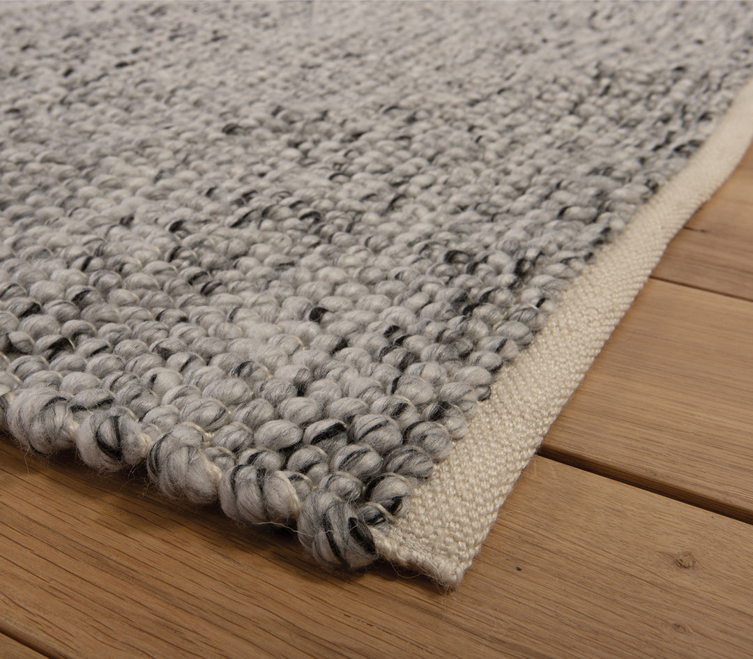 Κοντινή λήψη γκρι χαλιού με φυσική πλεκτή ύφανση.