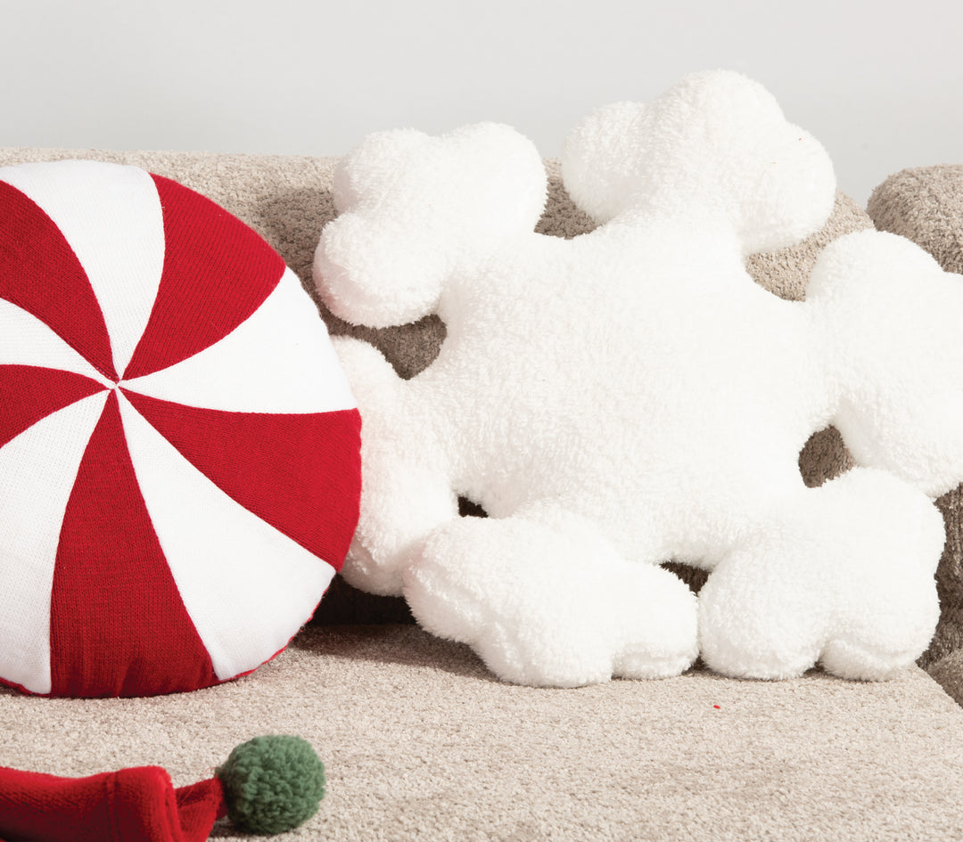 Λευκό αφράτο μαξιλάρι σε σχήμα χιονονιφάδας τοποθετημένο σε καναπέ, πλάι σε στρογγυλό μαξιλάρι κόκκινο-λευκό τύπου ζαχαρωτού