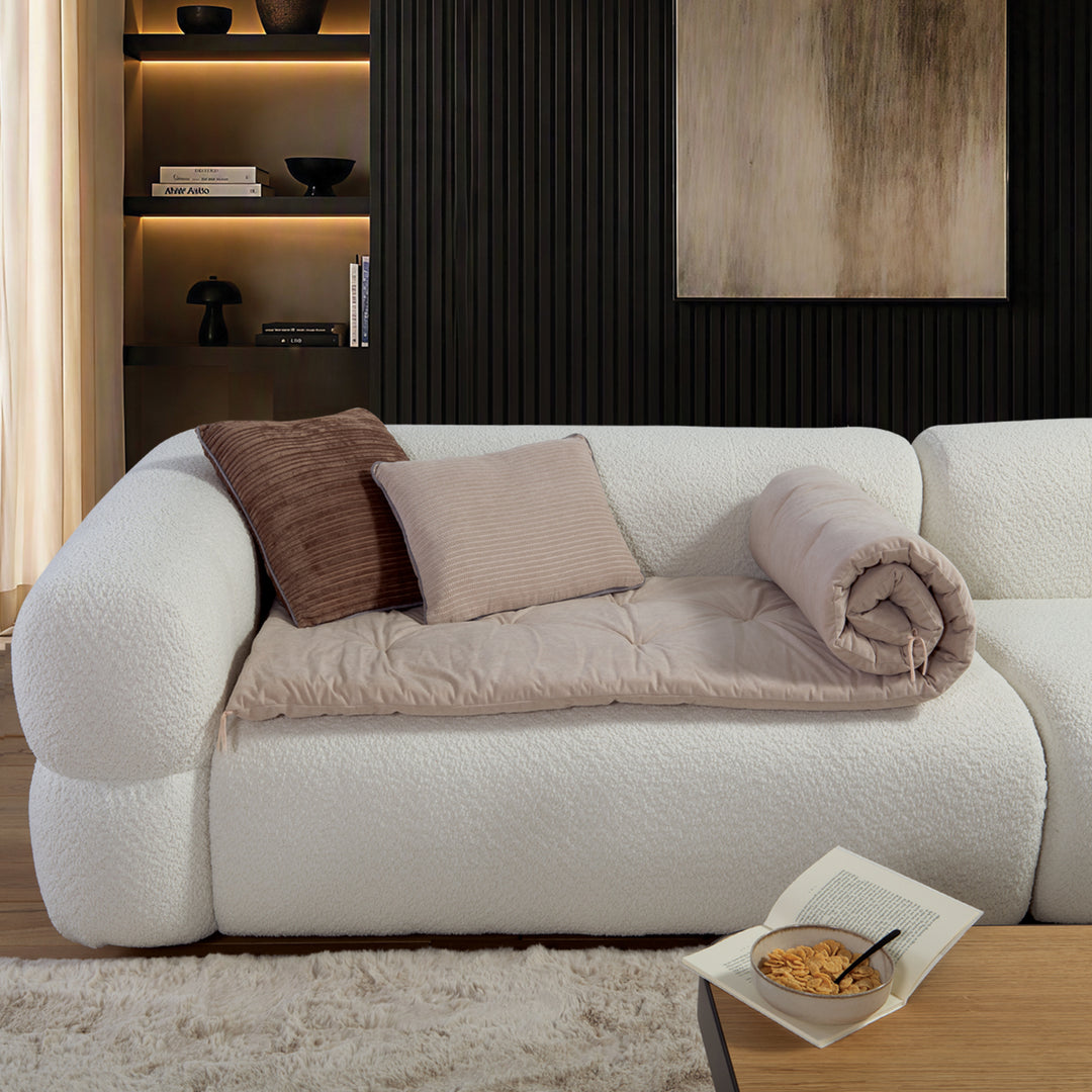 Μπεζ ανώστρωμα καναπέ Eriete Nef-Nef Homeware απλωμένο σε λευκό καναπέ, συνδυασμένο με διακοσμητικά μαξιλάρια σε γήινες αποχρώσεις.