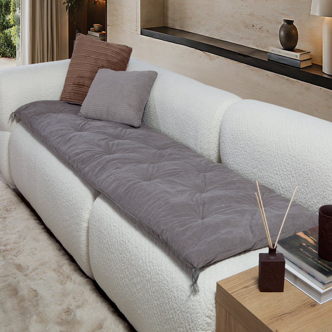 Γκρι ανώστρωμα καναπέ Eriete Nef-Nef Homeware απλωμένο σε λευκό καναπέ, με καπιτονέ σχεδιασμό σε μοντέρνο σαλόνι.