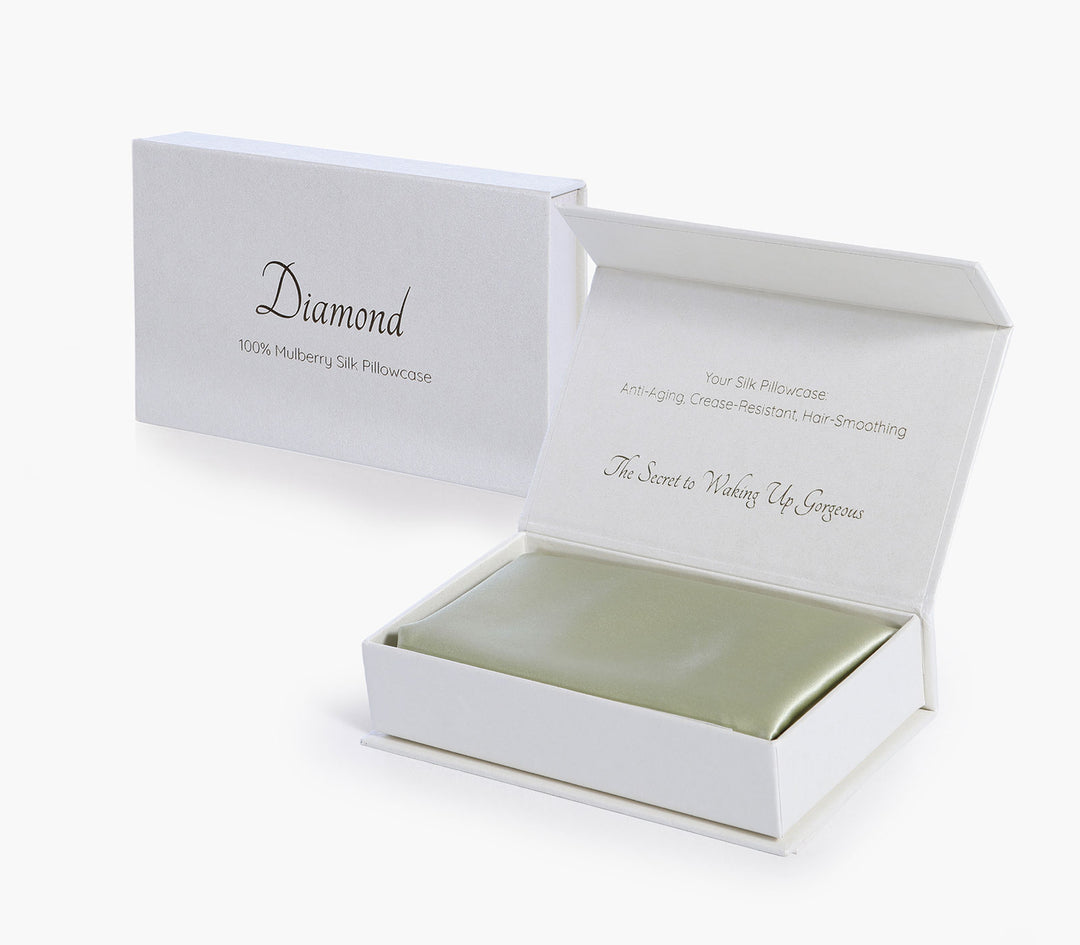 Μεταξωτή μαξιλαροθήκη σε λαδί απόχρωση τοποθετημένη σε κουτί συσκευασίας δώρου με λευκό φόντο.