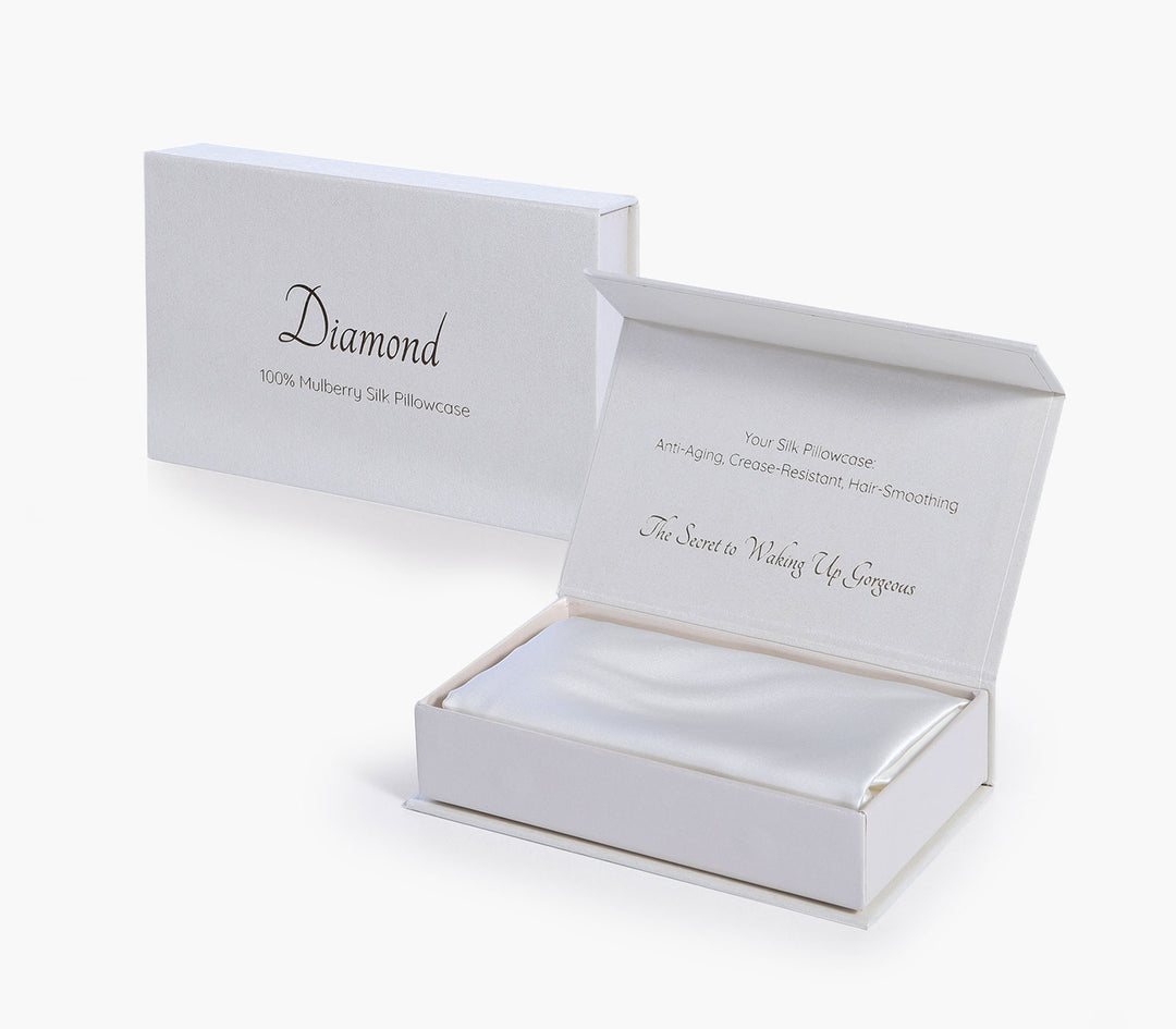 Μεταξωτή μαξιλαροθήκη σε λευκή απόχρωση τοποθετημένη σε κουτί συσκευασίας δώρου με λευκό φόντο.