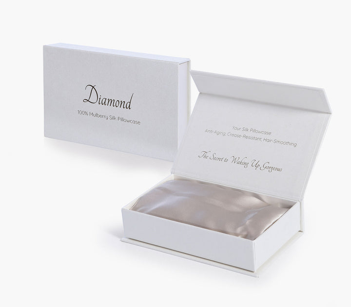 Μεταξωτή μαξιλαροθήκη σε μπεζ απόχρωση τοποθετημένη σε κουτί συσκευασίας δώρου με λευκό φόντο.