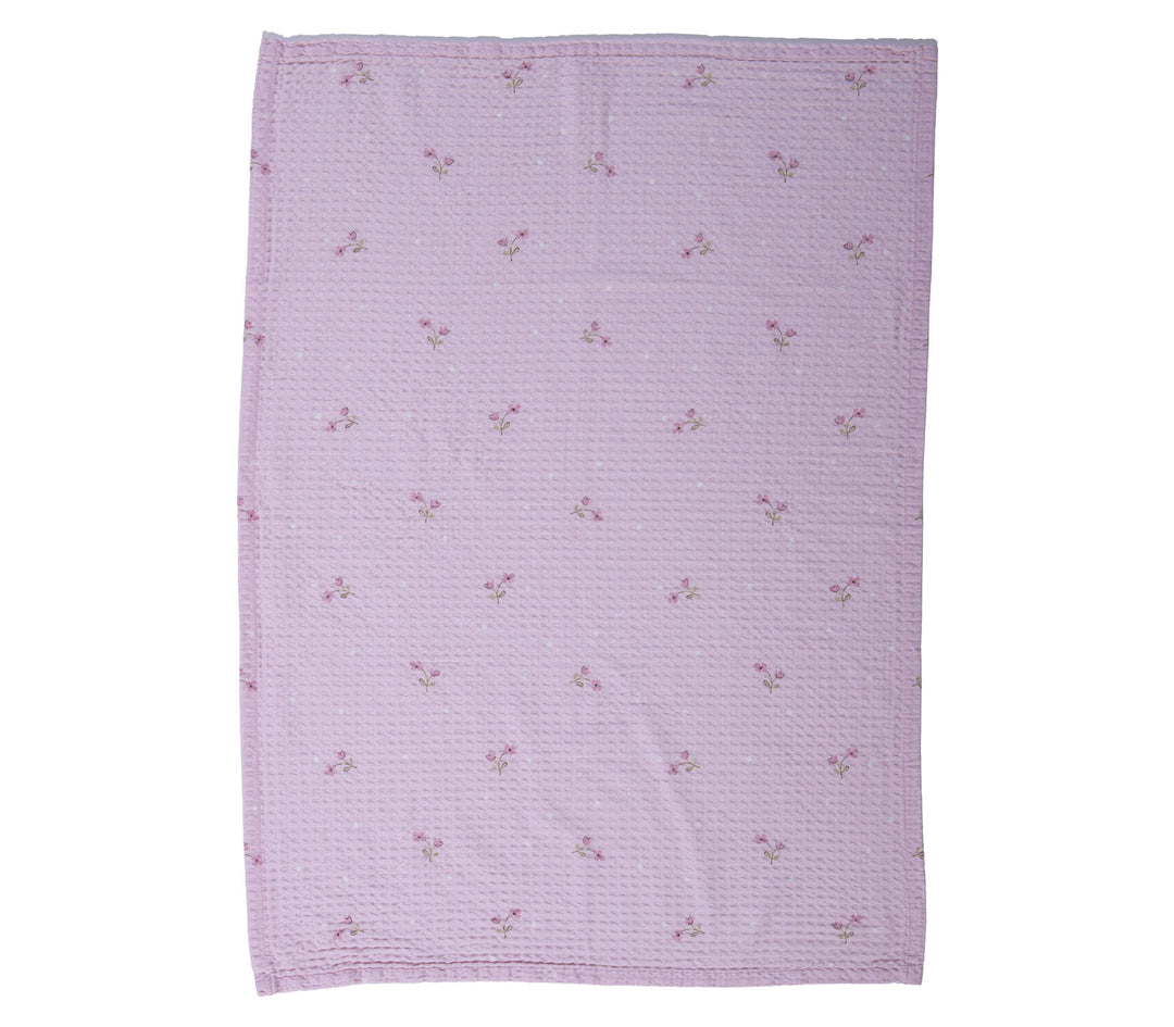 Βρεφική κουβέρτα πικέ κούνιας λιλά με μικρά λουλουδάκια απλωμένη σε λευκό φόντο φωτογράφισης.
