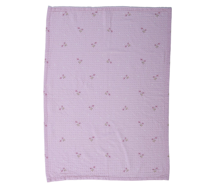 Βρεφική κουβέρτα πικέ κούνιας λιλά με μικρά λουλουδάκια απλωμένη σε λευκό φόντο φωτογράφισης.