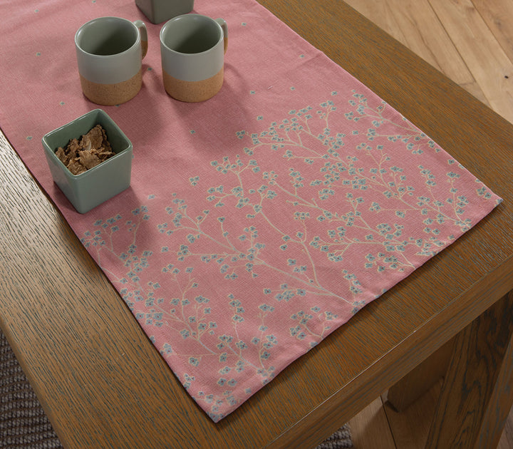 Κοραλί βαμβακερή τραβέρσα Floriva της Nef-Nef Homeware σε ξύλινο τραπέζι με διακριτικό φλοράλ σχέδιο και minimal σερβίρισμα.