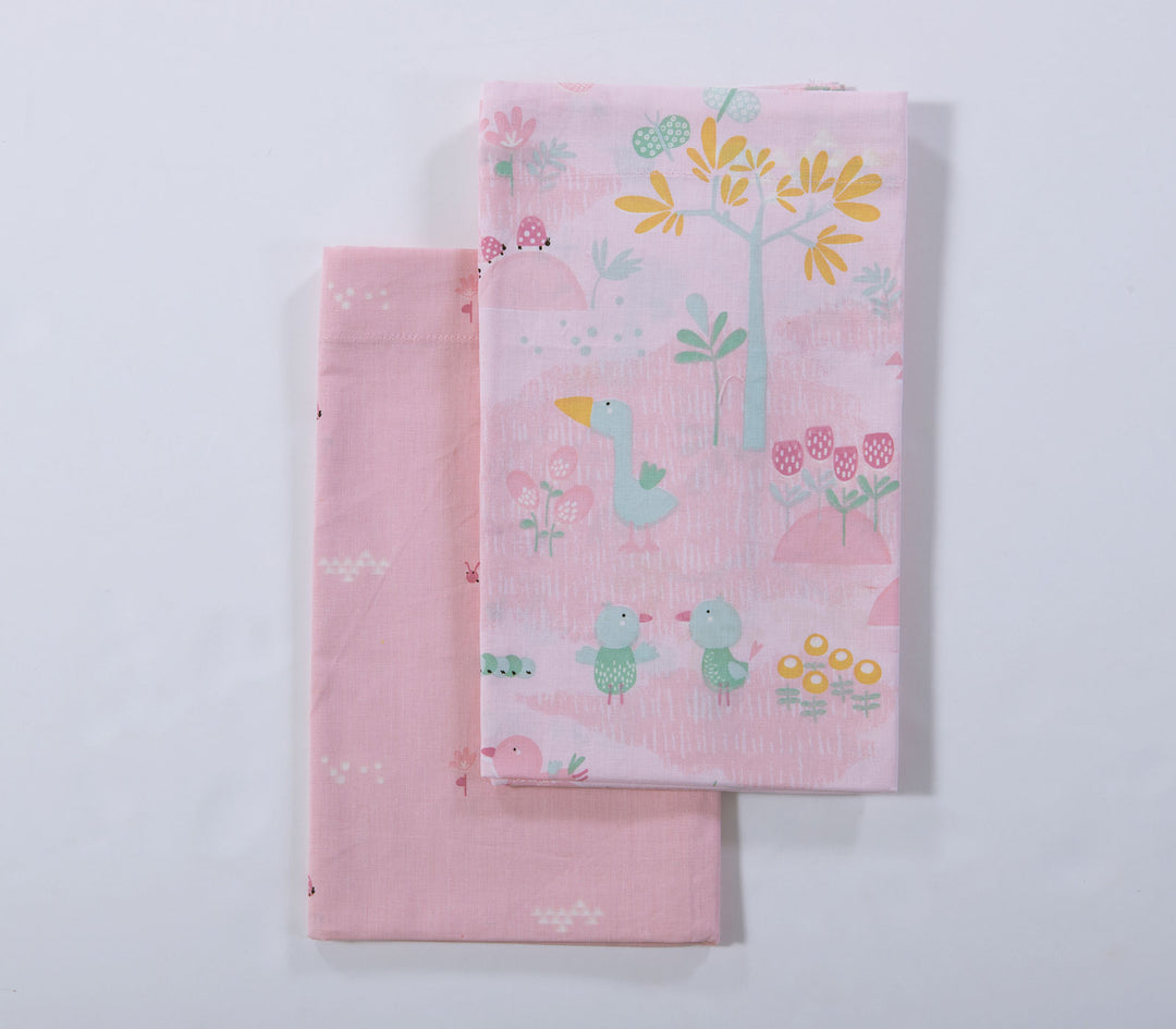 Δύο ροζ βρεφικά σεντόνια λίκνου με παιδικά σχέδια ζώων και φύσης τοποθετημένα σε λευκό φόντο.