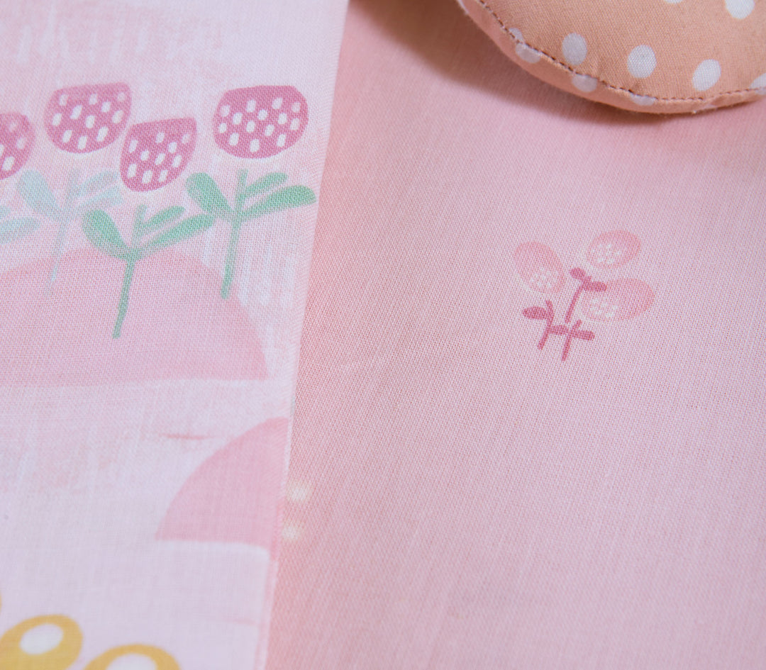 Κοντινό πλάνο ροζ βρεφικών σεντονιών λίκνου με λεπτομέρειες από λουλούδια και παστέλ σχέδια.