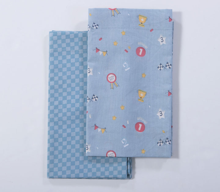 Διπλωμένα γαλάζια βρεφικά σεντόνια λίκνου με μοτίβα τρόπαια, σημαιάκια αγώνα και καρό σχέδιο σε λευκό φόντο.