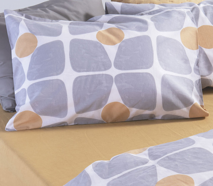 Μαξιλαροθήκες ύπνου με γεωμετρικό σχέδιο σε γκρι και κίτρινες αποχρώσεις τοποθετημένες πάνω σε κρεβάτι με μονόχρωμα σεντόνια.