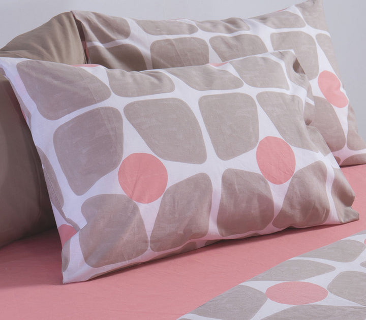 Μαξιλαροθήκη ύπνου σε μπεζ και κοραλλί αποχρώσεις με γεωμετρικό σχέδιο τοποθετημένη πάνω σε ροζ σεντόνι.