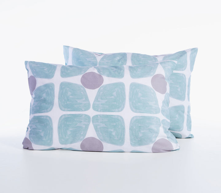 Δύο βαμβακερές μαξιλαροθήκες ύπνου σε τιρκουάζ και γκρι αποχρώσεις με γεωμετρικό σχέδιο σε λευκό φόντο.