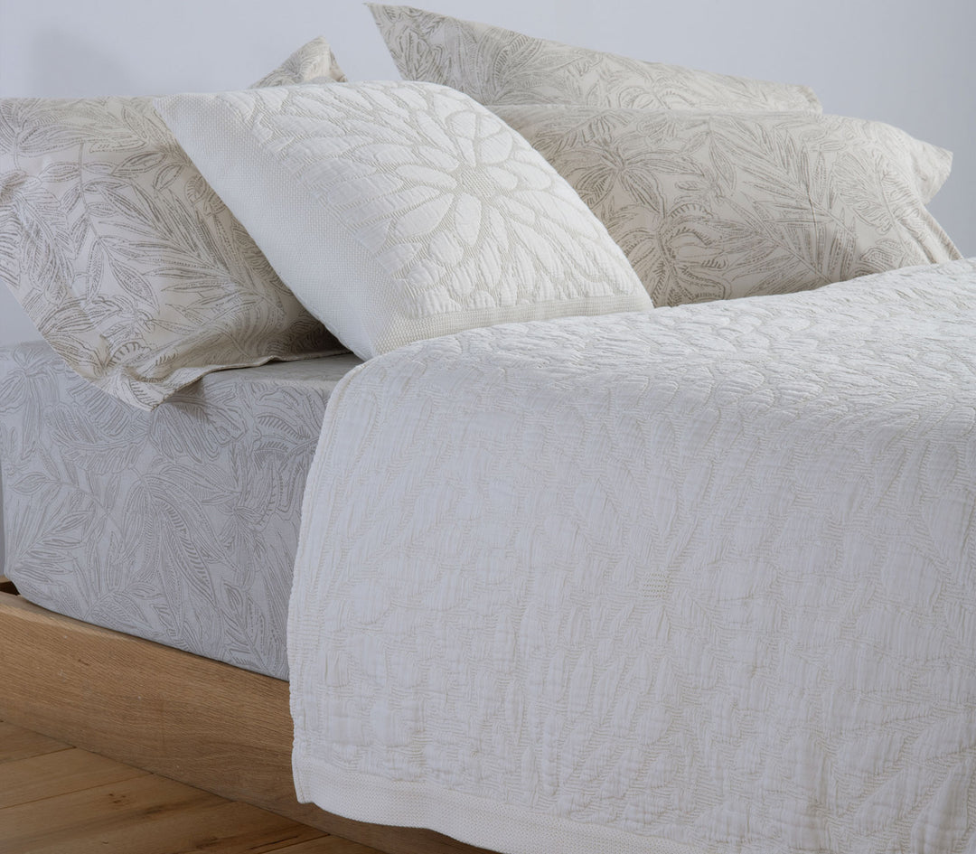 Διακοσμητική μαξιλαροθήκη Nef-Nef Homeware σε μπεζ-λευκή απόχρωση πάνω σε κρεβάτι, με ανάγλυφο φυτικό σχέδιο.