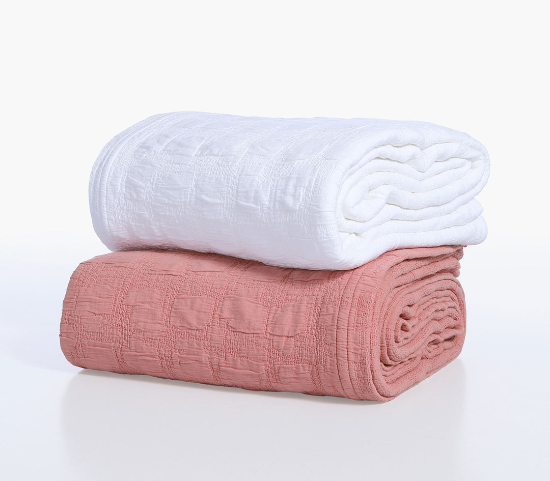 Διπλωμένες βαμβακερές κουβέρτες Nef-Nef Homeware σε λευκό και κοραλί χρώμα με ζακάρ υφή τοποθετημένες σε λευκό φόντο.