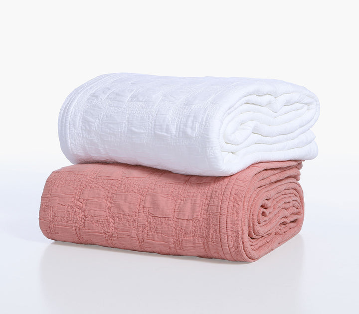 Διπλωμένες βαμβακερές κουβέρτες Nef-Nef Homeware σε λευκό και κοραλί χρώμα με ζακάρ υφή τοποθετημένες σε λευκό φόντο.