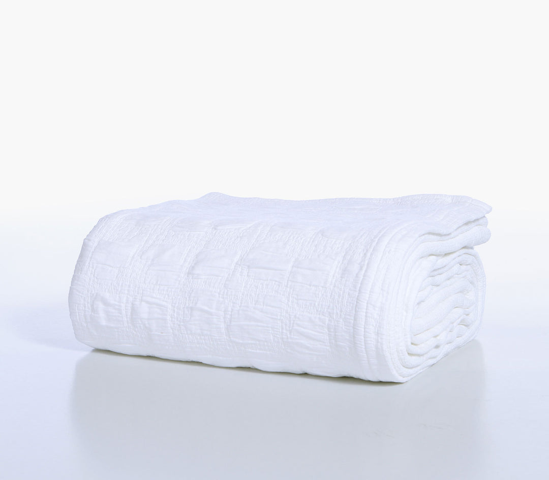 Διπλωμένη λευκή βαμβακερή κουβέρτα Nef-Nef Homeware με ανάγλυφο ζακάρ σχέδιο σε λευκό φόντο.