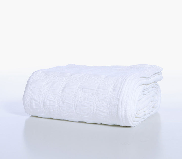 Διπλωμένη λευκή βαμβακερή κουβέρτα Nef-Nef Homeware με ανάγλυφο ζακάρ σχέδιο σε λευκό φόντο.