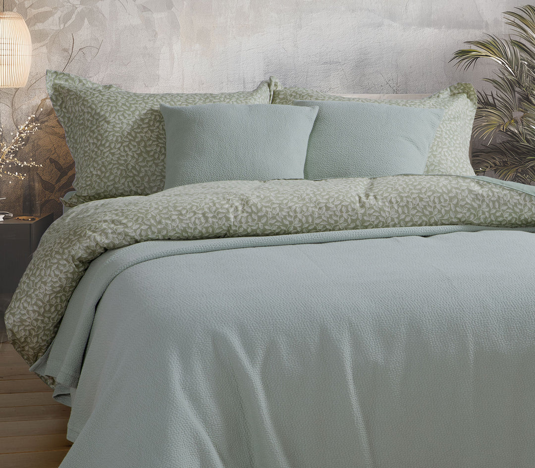 Κρεβάτι στρωμένο με βαμβακερή κουβέρτα Nef-Nef Homeware σε απαλό πράσινο χρώμα και σετ σεντονιών με φυλλωτό μοτίβο.