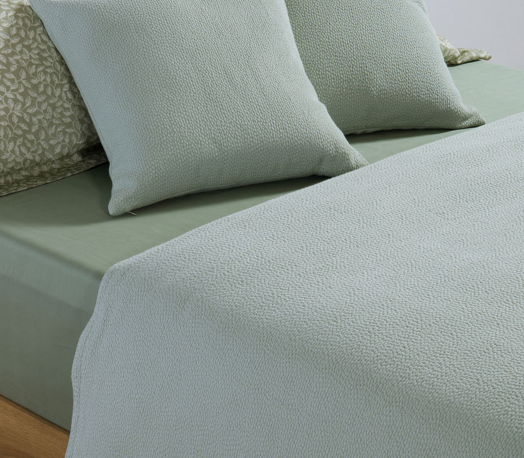 Υπέρδιπλη βαμβακερή κουβέρτα Nef-Nef Homeware σε απαλό πράσινο χρώμα στρωμένη σε κρεβάτι με διακοσμητικά μαξιλάρια.