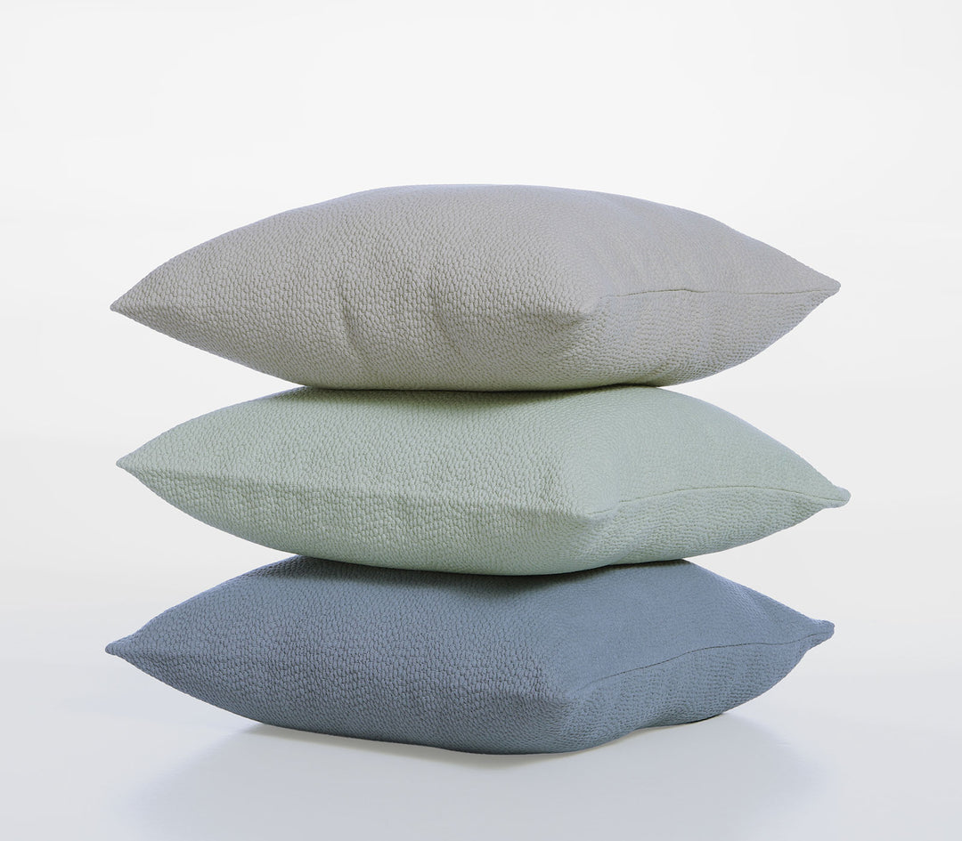 Τρεις διακοσμητικές μαξιλαροθήκες Nef-Nef Homeware σε μπεζ, πράσινο και μπλε χρώμα στοιβαγμένες.