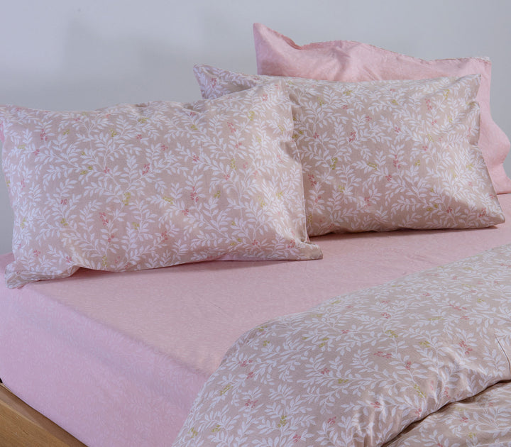 Μπεζ βαμβακερές μαξιλαροθήκες Nef-Nef Homeware με φλοράλ σχέδιο πάνω σε κρεβάτι με ροζ σεντόνι.
