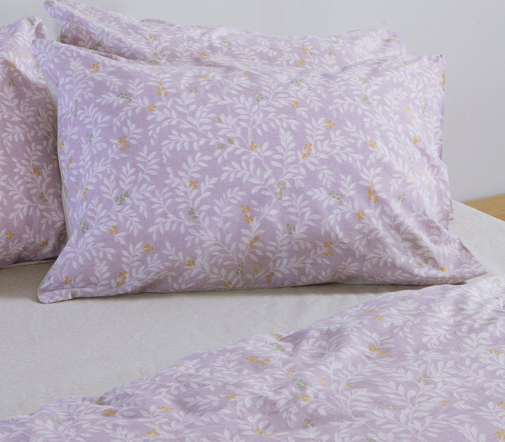 Λιλά βαμβακερή μαξιλαροθήκη Nef-Nef Homeware με φυτικό μοτίβο τοποθετημένη πάνω σε στρωμένο κρεβάτι.