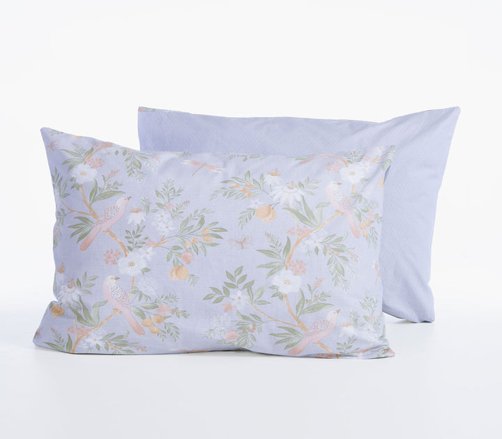 Μαξιλαροθήκη ύπνου Dreamel σε απαλό γαλάζιο χρώμα με πουλάκια και λουλούδια, μπροστά από μονόχρωμη γαλάζια μαξιλαροθήκη.
