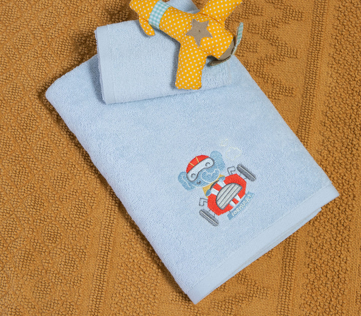 Σετ γαλάζιες βρεφικές πετσέτες με κεντημένο αρκουδάκι σε αυτοκίνητο τοποθετημένες πάνω σε υφασμάτινο χαλάκι.