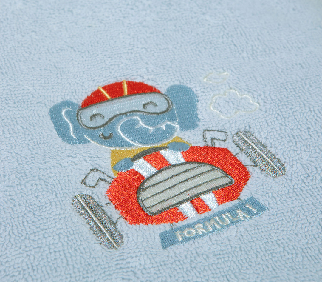 Κοντινό πλάνο γαλάζιας βρεφικής πετσέτας με κεντημένο αρκουδάκι που οδηγεί αγωνιστικό αυτοκίνητο.