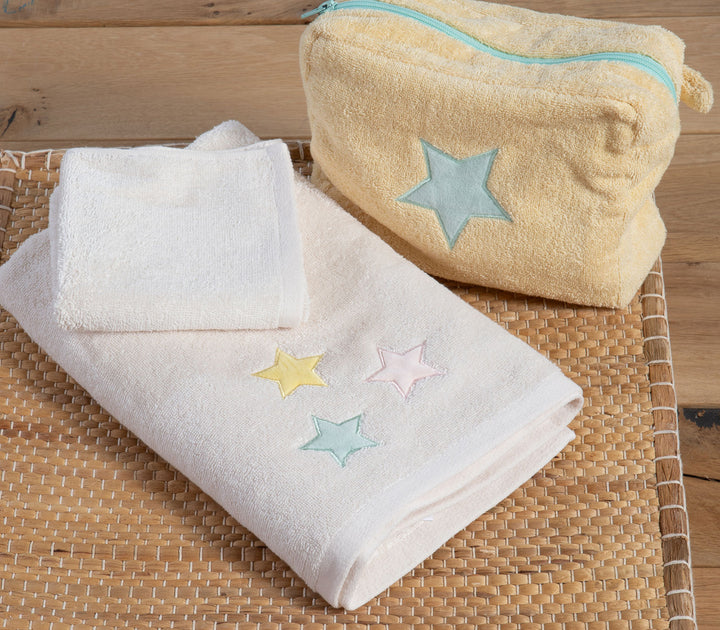 Βρεφικές πετσέτες εκρού με κεντημένα αστέρια τοποθετημένες σε ψάθινο δίσκο μαζί με νεσεσέρ.
