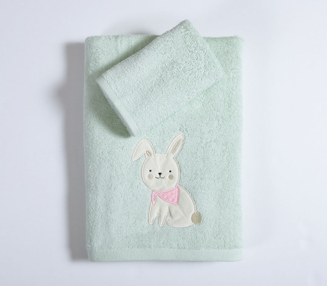 Διπλωμένες βρεφικές πετσέτες πράσινες με σχέδιο λαγουδάκι σε καθαρό λευκό φόντο φωτογράφισης.